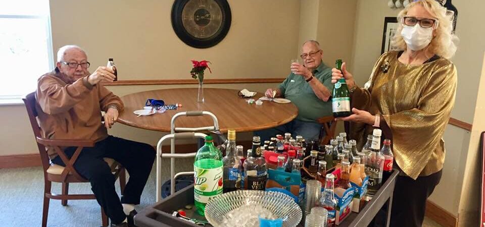 2 senior men enjoying a beer and a glass of champagne during a happy hour at Ecumen Meadows