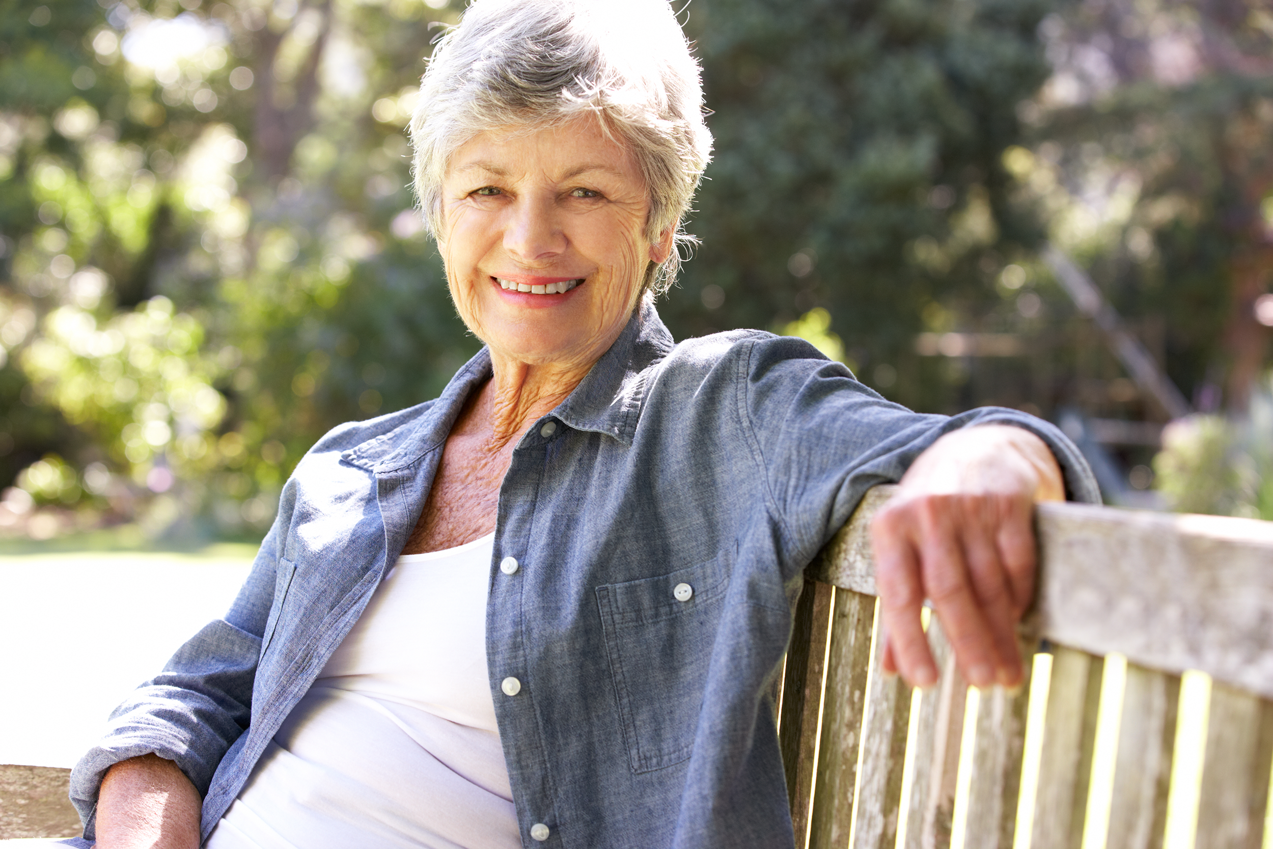 senior woman sitting in the sun on a bench