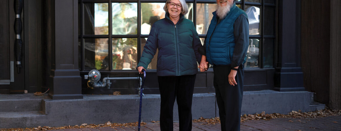 a senior woman with a cane with her spouse outside on a Fall day