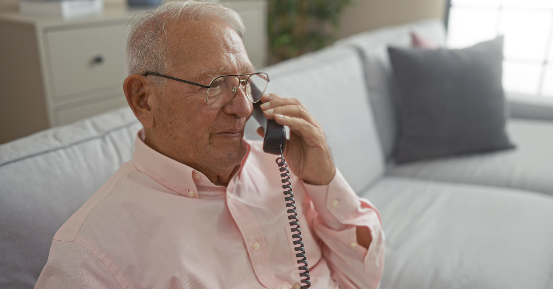 a senior male using a special phone for hearing impaired.