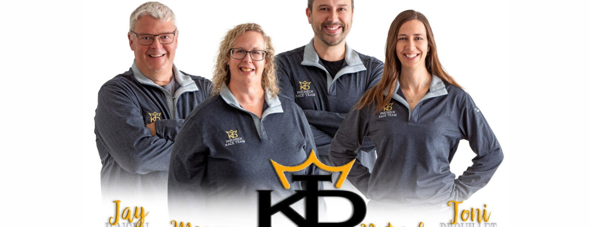 Four people in gray quarter-zip pullovers stand together