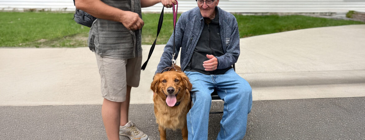 A golden retriever stands between two people on a paved path
